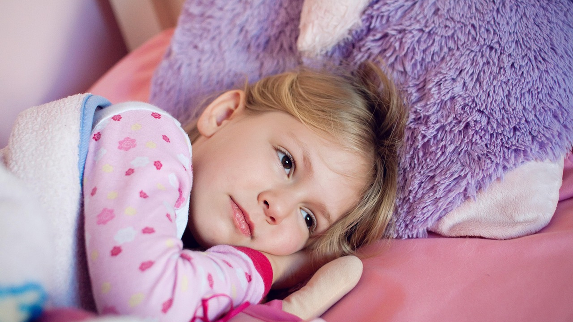 Child resting on a pillow in bed - lice on pillows is rarely how head lice spread