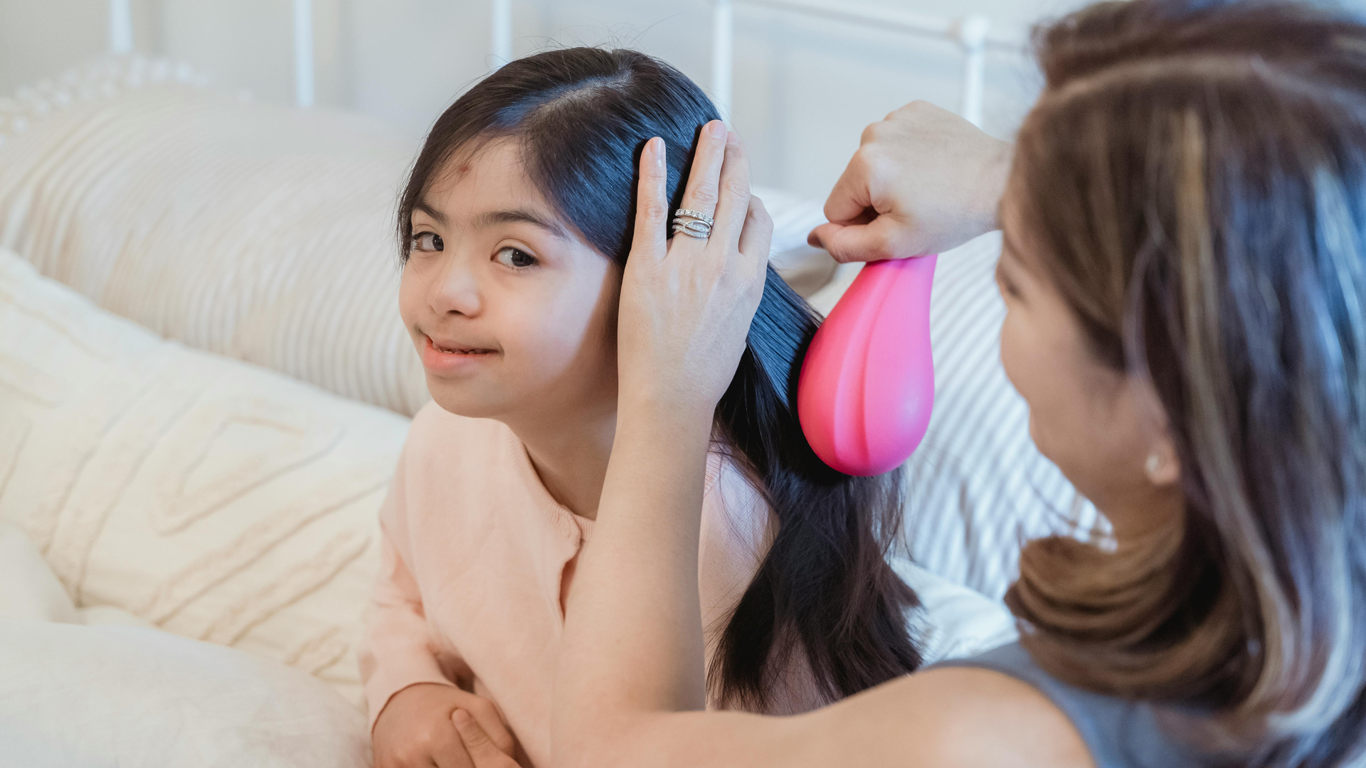 Mother combing through daughter's hair during a lice egg check at home