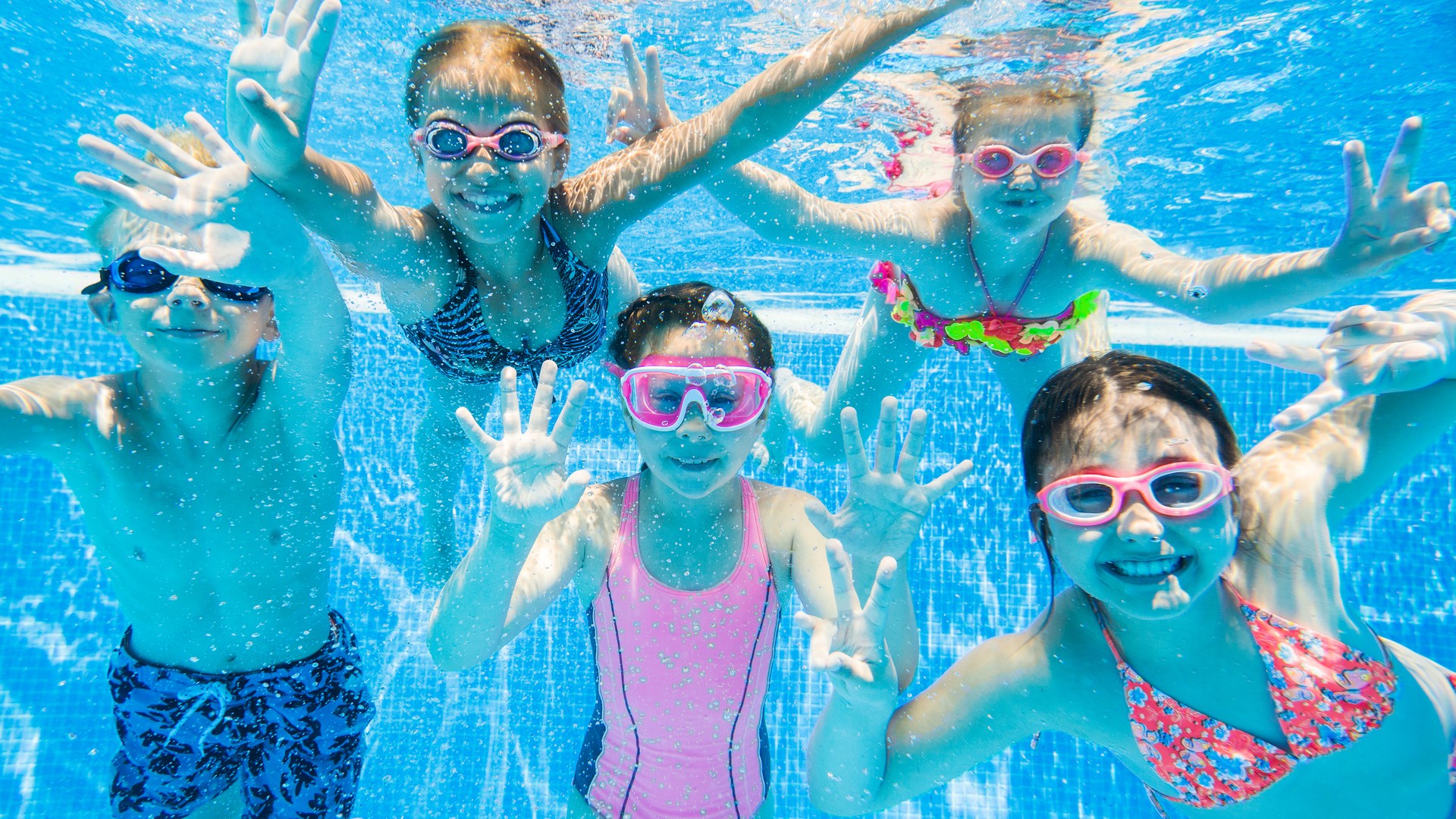 Young children swimming underwater in a community pool on a summer day, the scene a Union County parent pictures when wondering whether the pool will end their child's lice case.