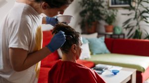 Adult helping a family member dye their hair at home, illustrating the home-remedy question of whether hair color treats head lice