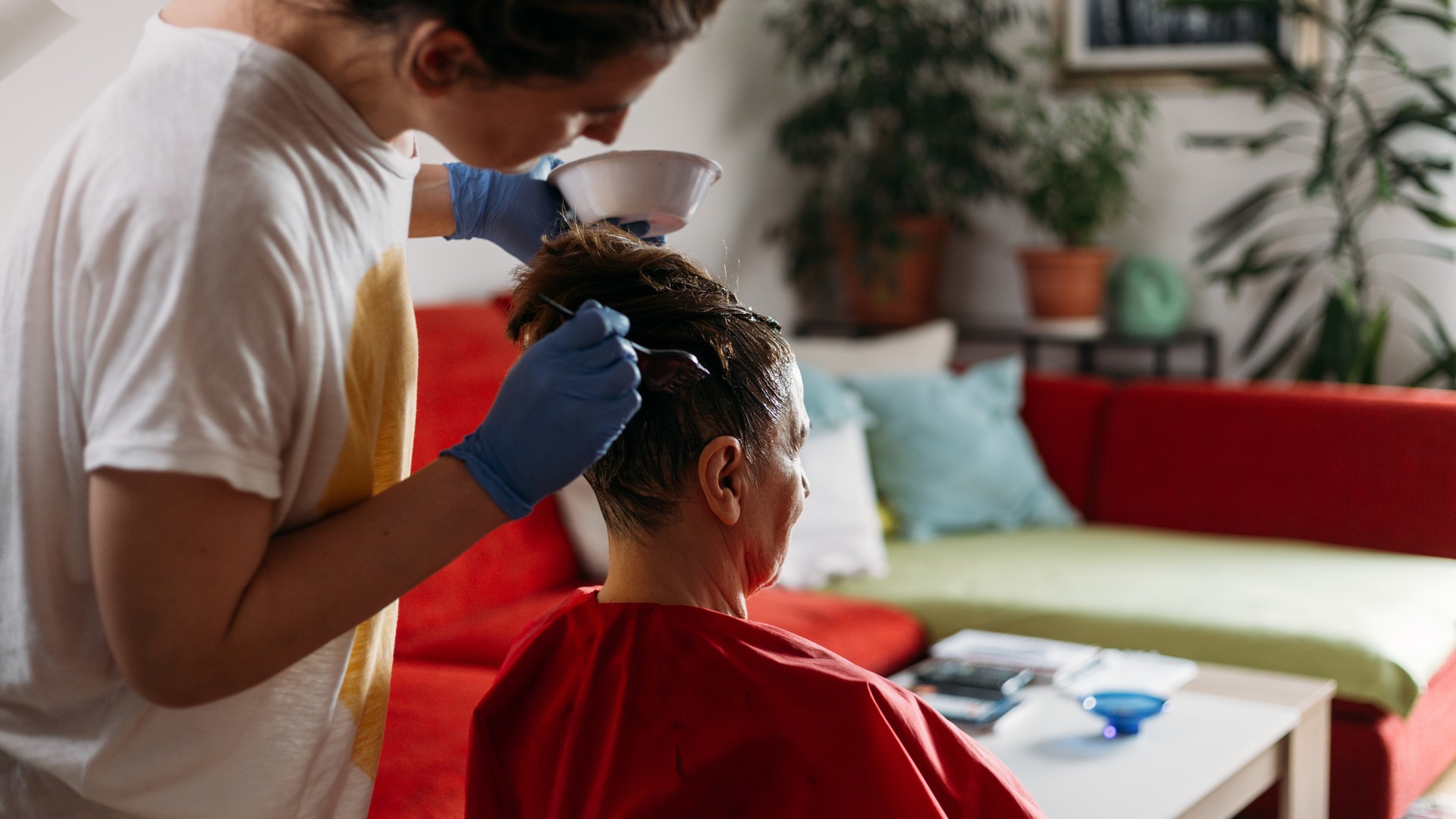 Adult helping a family member dye their hair at home, illustrating the home-remedy question of whether hair color treats head lice
