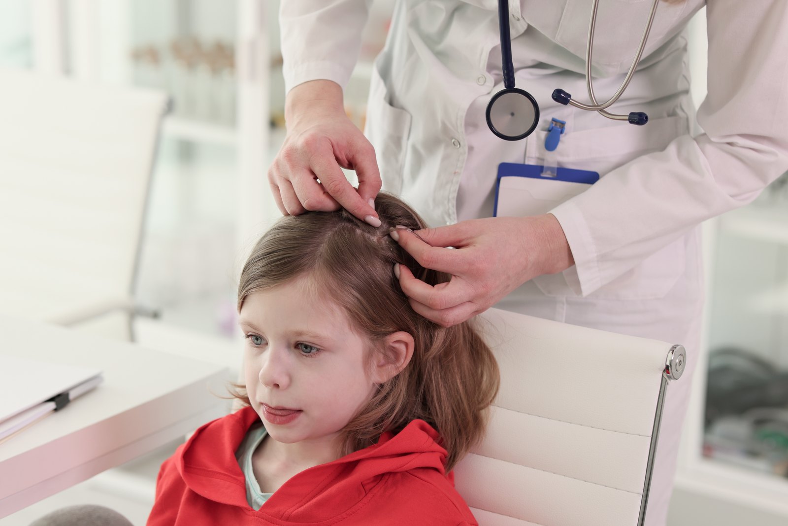 Professional lice-removal technician parting a child?s hair during a head check