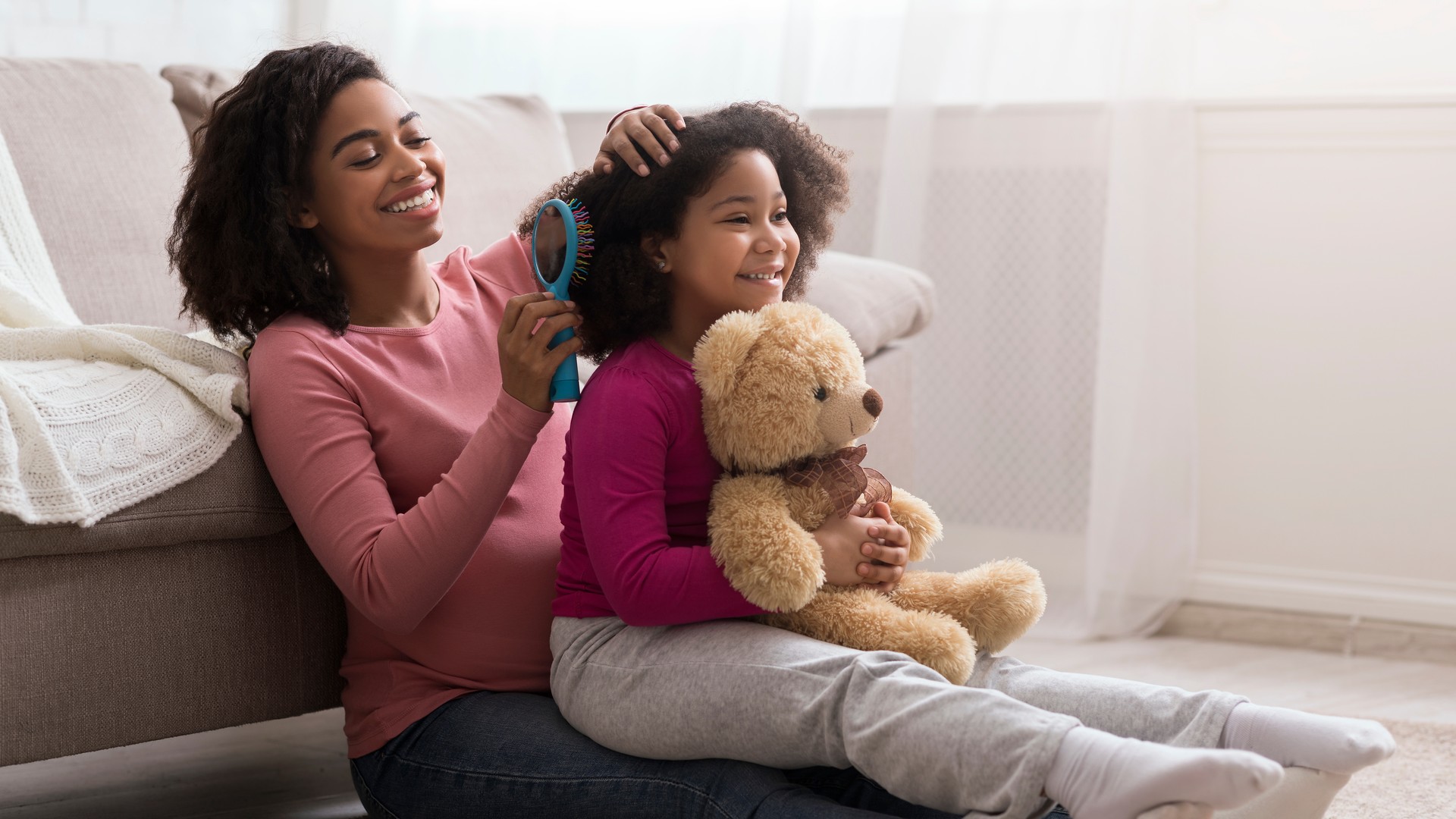 Pregnant mom gently combing her child's hair at home during lice treatment