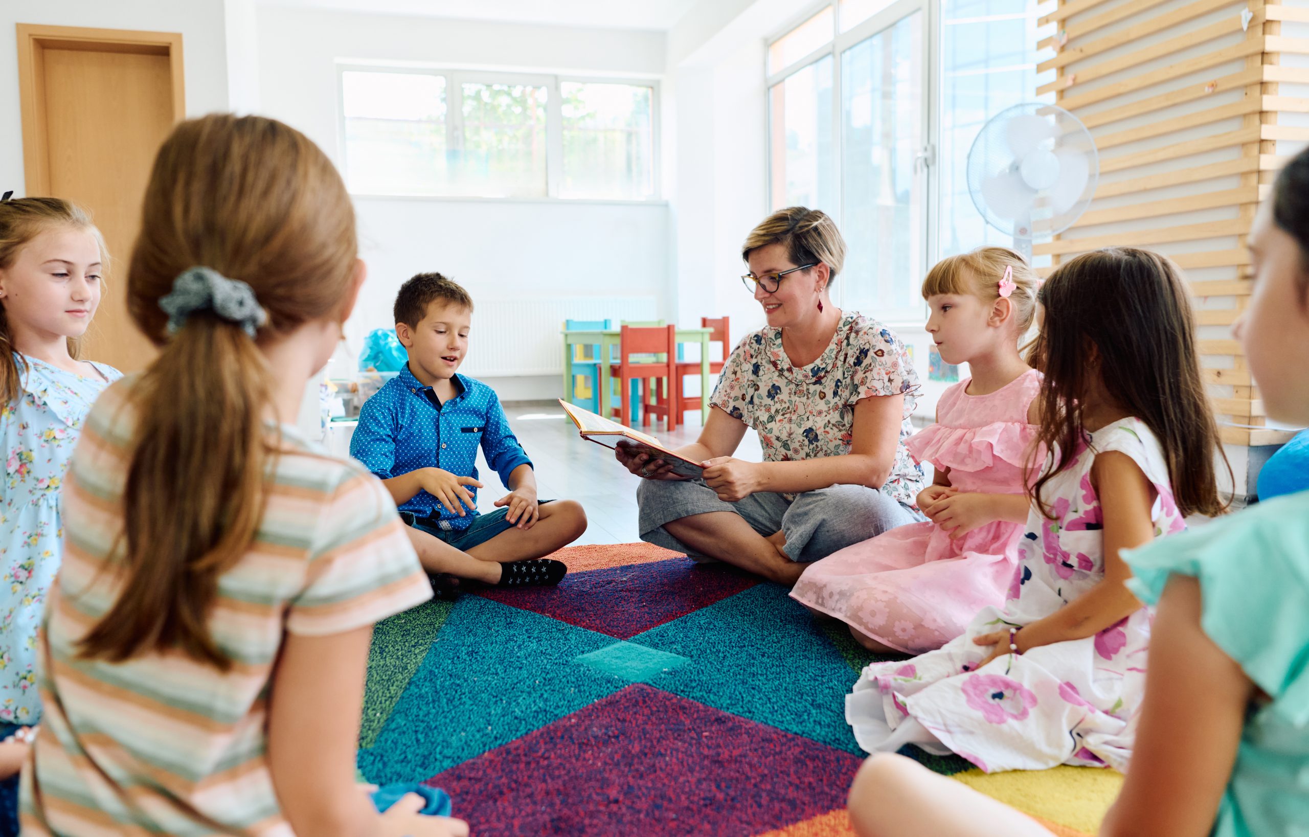 Preschool teacher reading to children during classroom circle time