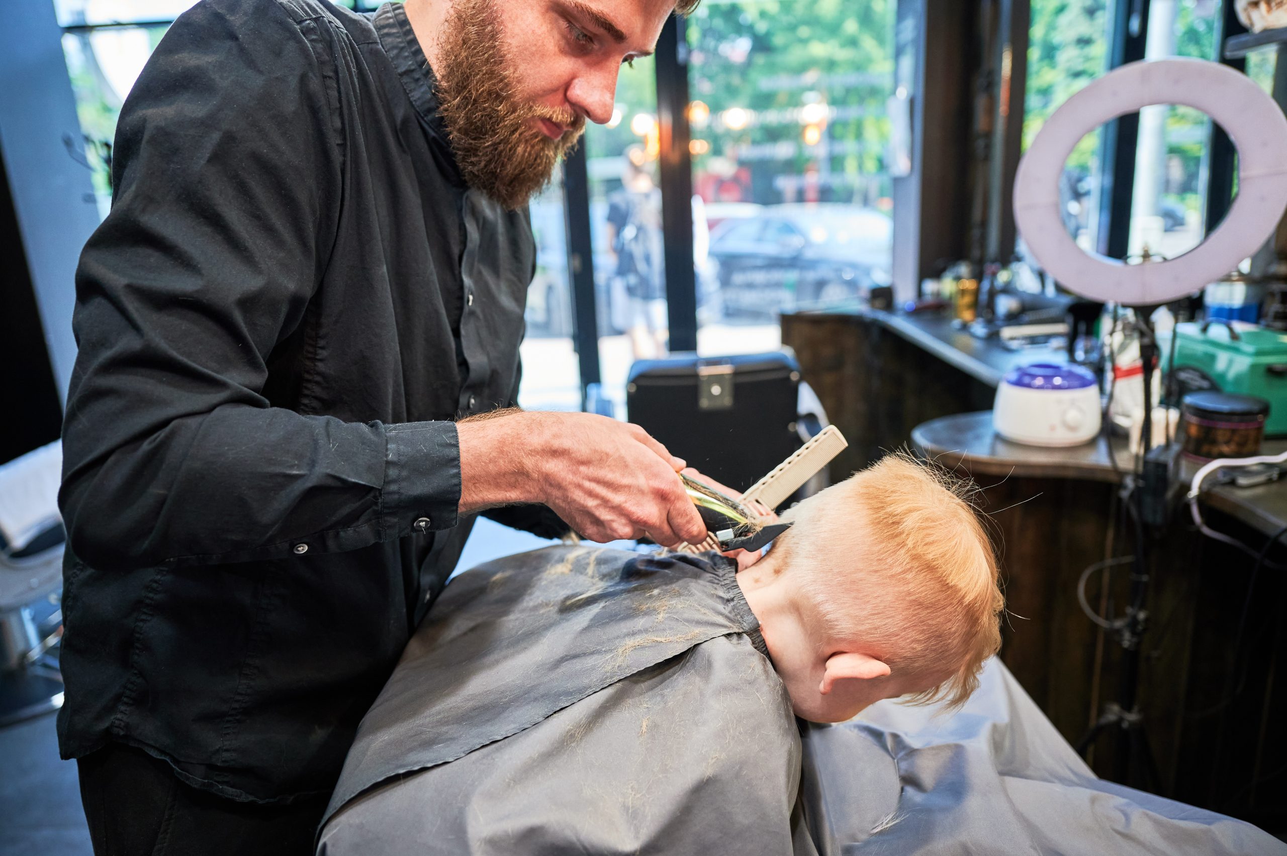 Child getting a haircut with clippers for a shaving head lice article