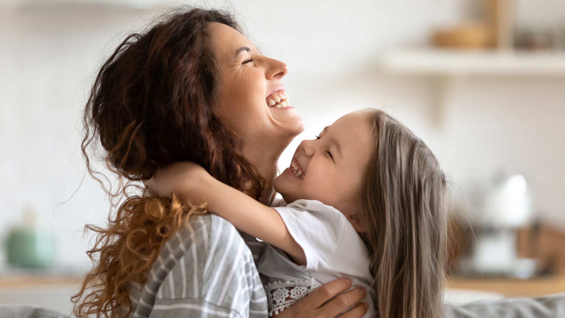 A parent and young child mid-hug, cheek against shoulder with their scalps apart, showing that an ordinary hug rarely puts hair against hair